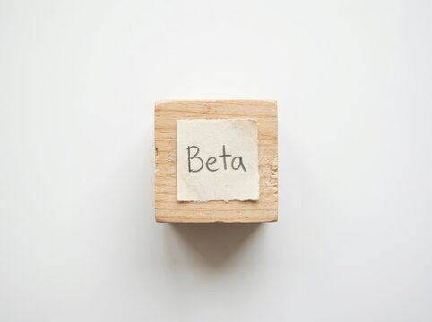 Wooden block with Beta paper note on white background