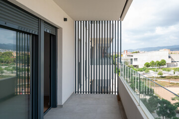 Obraz premium Modern apartment balcony with glass railing and louver privacy screen