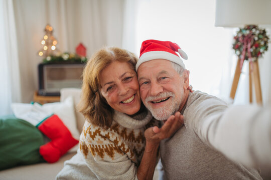 Senior couple making Christmas selfie for family during holidays at home.