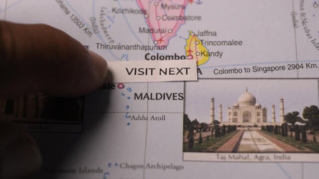 Hand Placing Visit Next Note on Maldives Map for Travel Destination Concept