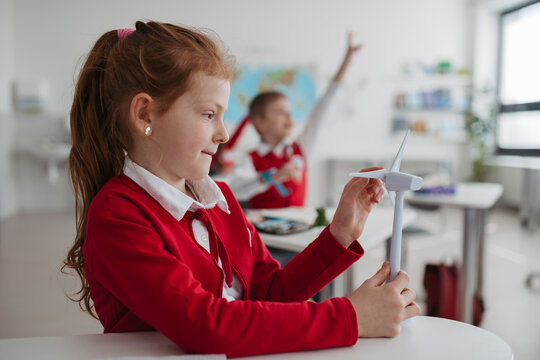 Teacher teaching primary school students about renewable wind energy.