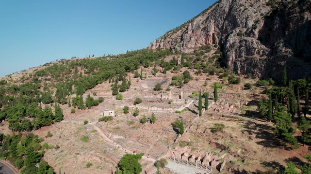 Aerial view of the ancient ruins of Delphi nestled on the slopes of Mount Parnassus with stone columns and historic archaeological remains in Delphi, Greece.