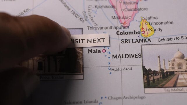Hand placing VISIT NEXT note on a travel map for vacation planning concept