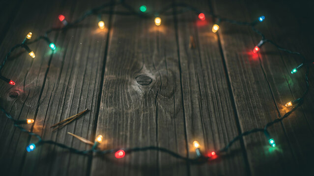 Festive christmas string lights arranged in a circle on a rustic dark wooden background with copy space