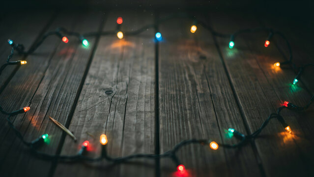 Christmas string lights arranged in a circle on a rustic dark wooden background