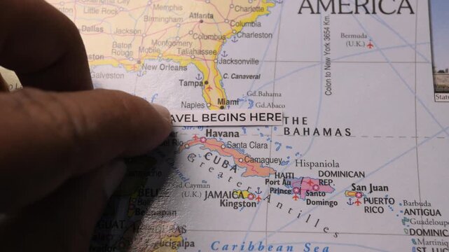 Hand places Travel Begins Here text strip on world map for vacation planning