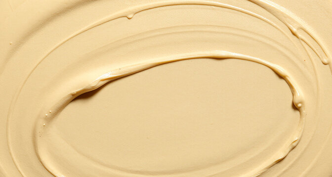 creamy beige liquid foundation cosmetic face makeup texture spread in smooth circular swirl stroke close up top view macro product photograph