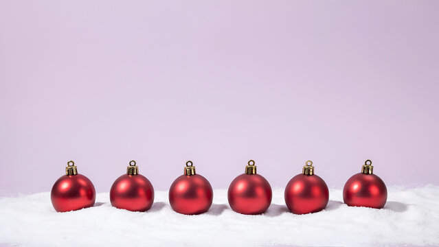 Six red christmas ornaments in a row on snow against a soft purple background