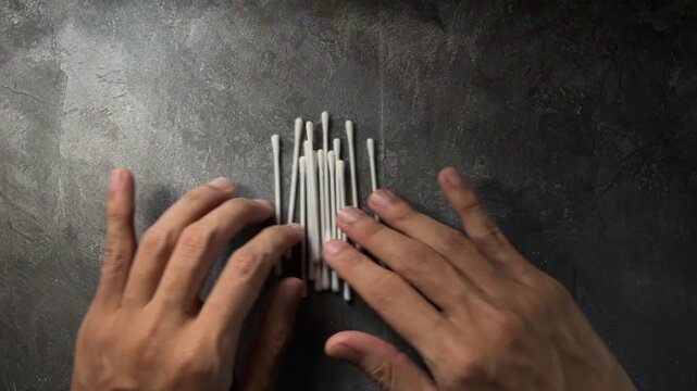 Hands aligning cotton swabs in neat rows on table