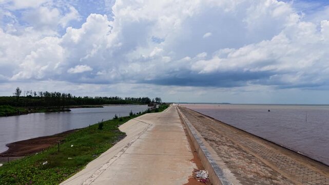 Visit Con Nhan Beach in Vinh Long, Vietnam. Walk along the path by the water while enjoying the view and the sky. Watch people relax and boats move along the river.