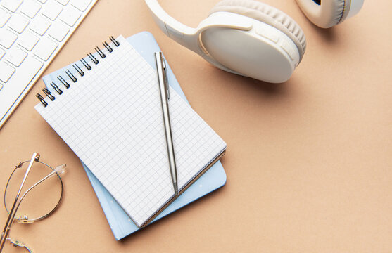 Workspace with notebook, pen, headphones, and keyboard