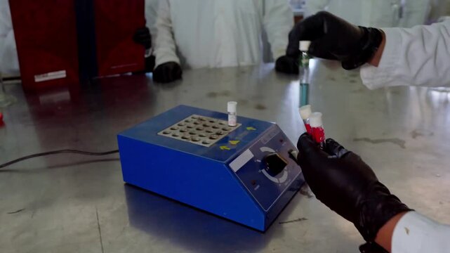Close-up of scientists in lab coats and gloves, meticulously placing test tubes filled with samples into a specialized laboratory instrument for analysis. Emphasizes research and quality control in ag