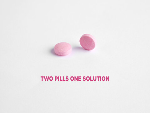 Two pink pills providing one solution on white background