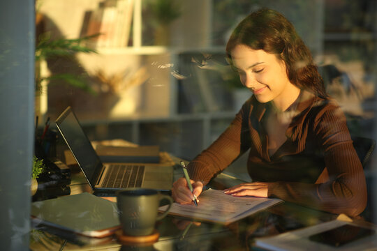 Telecommuter filling out form at sunset working at home
