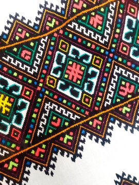 Close-up of traditional Ukrainian Hutsul geometric embroidery with colorful diamond patterns and textured thread detail.