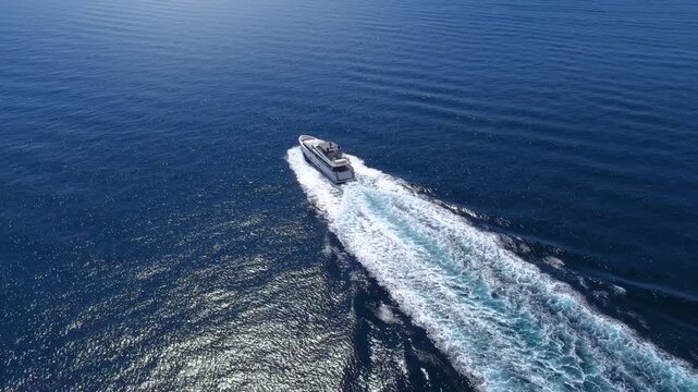 Aerial view of an modern luxury yacht cruising over the ocean leaving a trail of white surf and waves