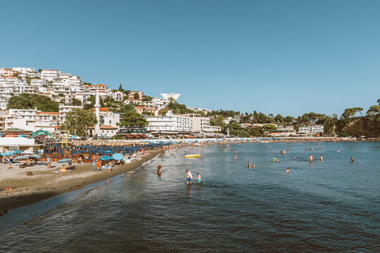 Ulcinj, Montenegro - August 10, 2025: Wide view of Mala Plaza beach with sunbathers, umbrellas and swimmers in the Adriatic Sea, with the coastal town skyline in Ulcinj, Montenegro