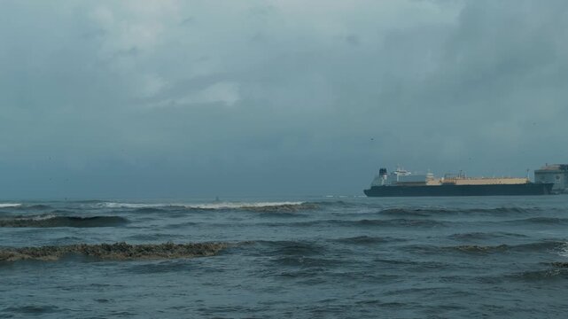 Sea with heavy waves and thick clouds as a ship pass by 