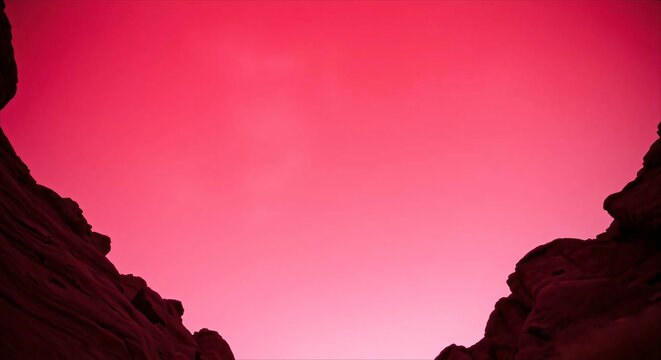 Vibrant pink sky with dark rock silhouettes.