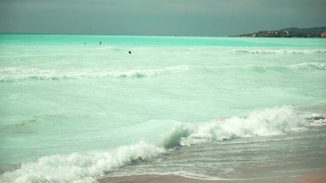 Spiagge Bianche, Italy. Turquoise sea waves washing up on a sandy beach shore in rosignano solvay, italy, with people swimming in the beautiful blue water on a summer day in tuscany