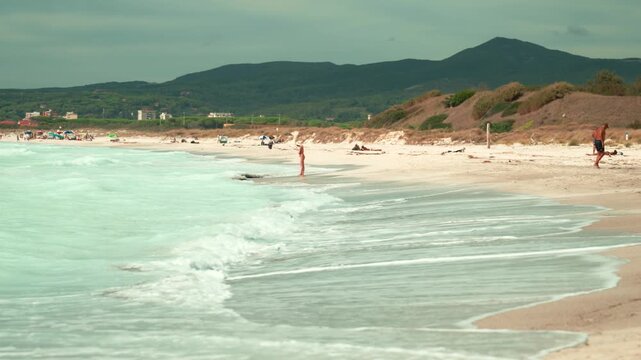 Tropical beach with gentle waves washing ashore on a beautiful summer day with hills in the background, spiagge bianche, Italy