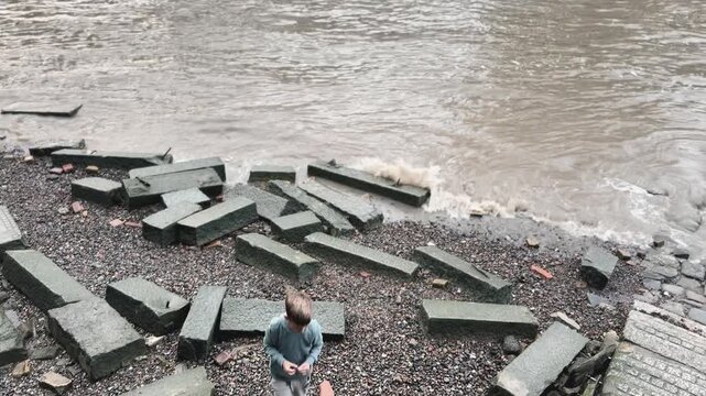 Child playing on Thames riverbank beside Tower Bridge in London