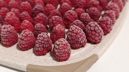 Frozen fresh red raspberries arranged on plastic board close up © eliyashevskiy