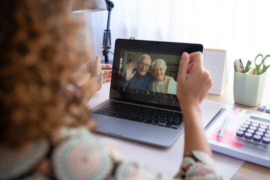 White woman video calling elderly couple on laptop