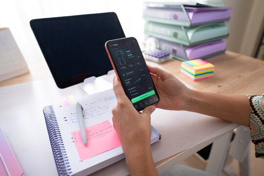 Hand holding smartphone displaying charging status by notebook
