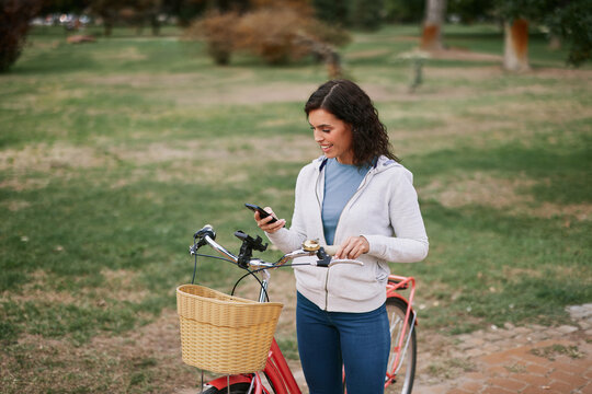 Woman using smartphone while standing with bicycle in autumn park