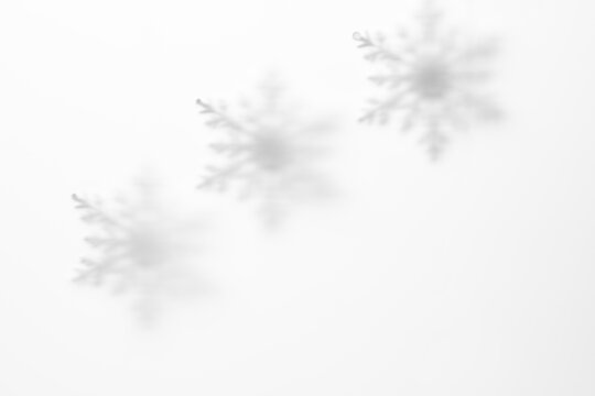 Soft snowflake shadows through matte glass on white winter background with copy space for Christmas greeting card, banner or seasonal design