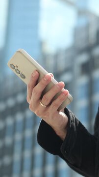 businessman hand hold smartphone and using investment application for trading or check email from company or surf the internet at outside building in the city for technology concept