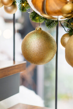 Luxurious golden Christmas bauble hanging on evergreen branch, sparkling holiday decoration with soft warm lights and elegant festive decor in bright modern interior, seasonal celebration