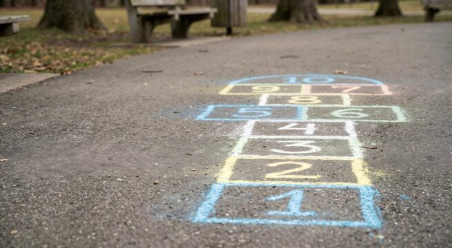 Colorful hopscotch grid drawn in chalk on park asphalt pavement. Classic outdoor children game for recreation and activity