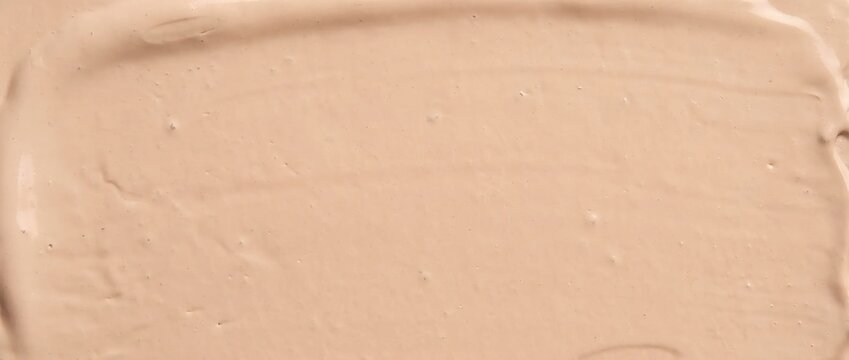 Smooth texture of liquid concealer cream. Nude beige foundation smear background for cosmetic design