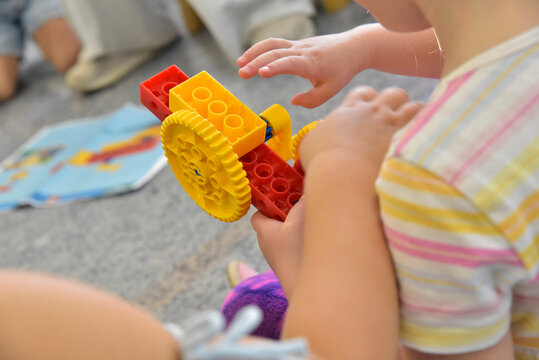 Child plays with yellow and red plastic toy building blocks