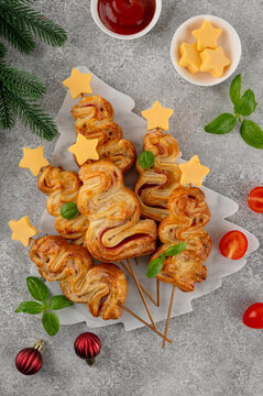 Puff pastry Christmas tree buns with cheese and ham on a marble board. Christmas and New Year appetizer. Top view, copy space.