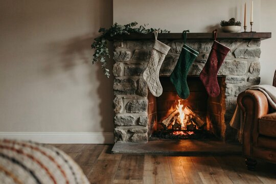 Christmas stockings hung above a stone fireplace with low firelight