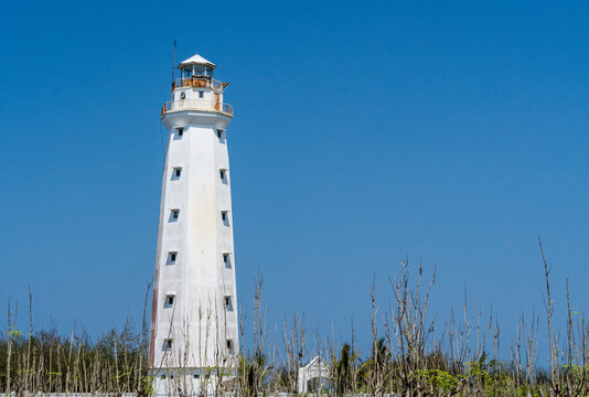 Tall white coastal lighthouse standing against a clear blue sky