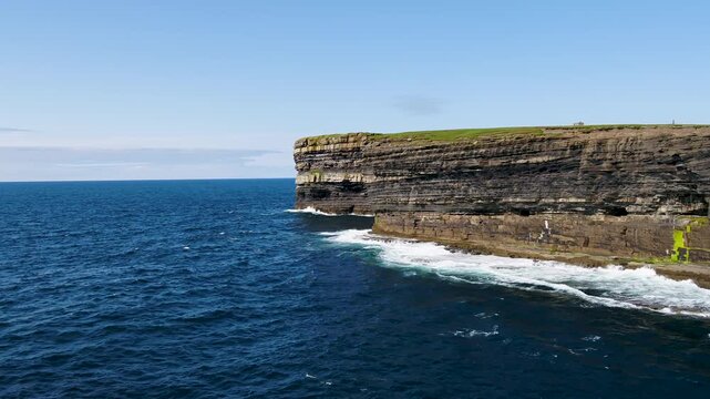 Aerial view of the dramatic Dun Briste Sea Stack rising from the Atlantic Ocean with rugged cliffs and green grassy clifftops in Ballycastle, County Mayo, Ireland.