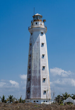 Tall white coastal lighthouse standing against a clear blue sky