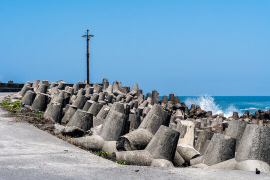 Concrete breakwater blocks line the sandy coast as ocean waves crash against them
