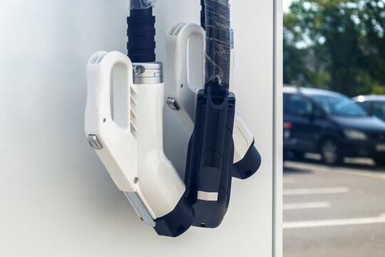 Electric vehicle charging connectors at public outdoor station in sunny parking lot
