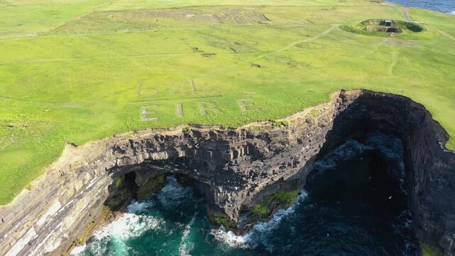 Aerial view of the dramatic Dun Briste Sea Stack and the historic EIRE 64 neutrality sign on the grassy cliff edge overlooking the Atlantic Ocean in Ballycastle, County Mayo, Ireland.