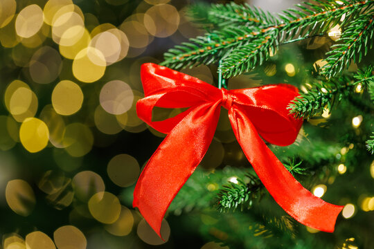 Red bow on Christmas tree with festive golden lights