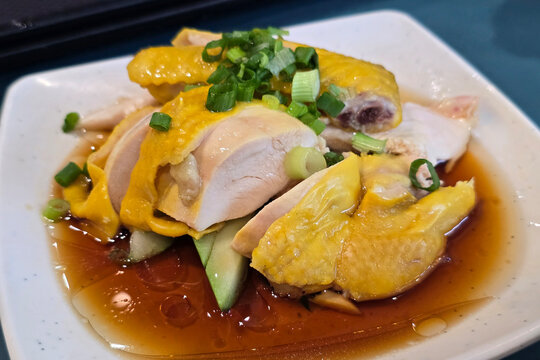 Steamed Hainanese Poached Chicken Served with Soy Sauce and Spring Onions.
