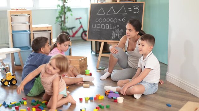 Kindergarten class. Teacher draws rules on the desk board. Children sit on the floor and memorize them . High quality 4k footage