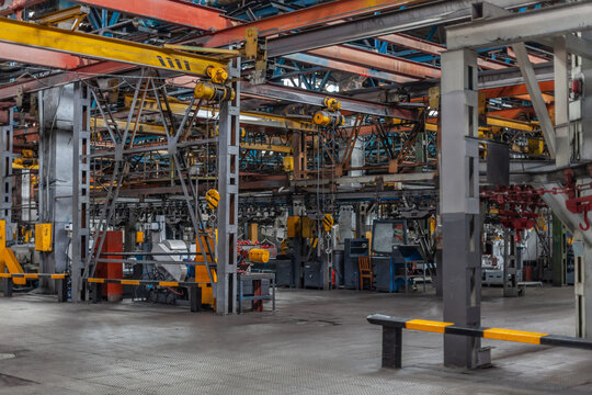 Interior view of a large heavy machinery manufacturing plant with industrial overhead cranes and steel structures. Industrial atmosphere of heavy-duty factory floor.