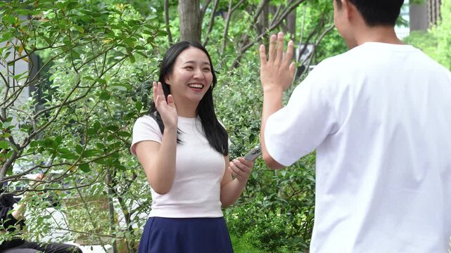 Japanese man and woman meeting on a street corner and chatting with smiles on a date