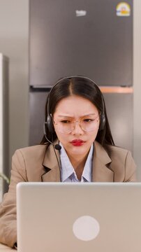 Frustrated Asian Businesswoman Wearing Headset Working on Laptop Remotely
